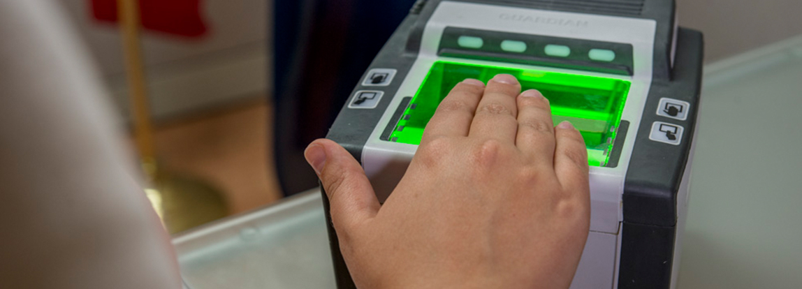 A person scanning their fingerprints on a mobile scanner